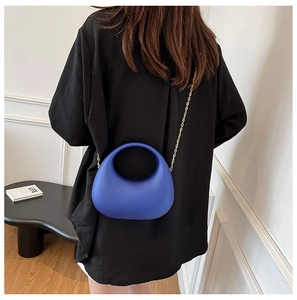 Détail d'une pochette de soirée en acrylique bleu foncé avec chaîne dorée sur le mannequin