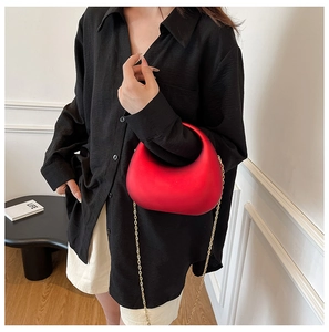 Chic red semi-circular acrylic evening bag with a gold metal chain strap on model