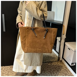 Detailed view of brown matte tote bag featuring stylish knotted black strap accents
