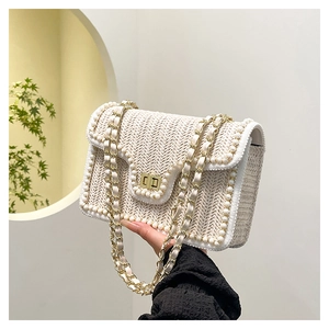 Détail du sac en paille blanche avec bordure perlée et bandoulière en chaîne dorée