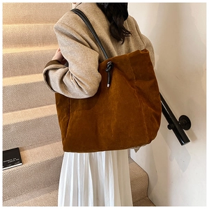 Detail of deep caramel frosted leather tote bag with elegant side knot on soft suede texture