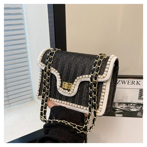 Détail du sac en paille tressée noire avec bordure en perles et fermoir doré