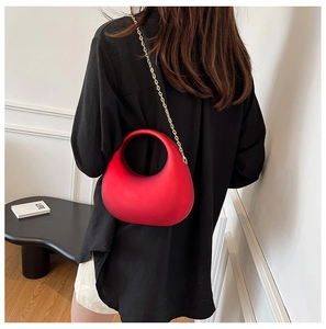 Détail du sac de soirée rouge en acrylique avec chaîne dorée sur le mannequin