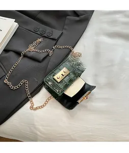 Detail view of dark green croc-embossed mini bag with gold chain and internal capacity