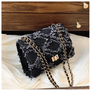 Detailed close-up of dark denim chain bag with frayed edges and golden rectangular twist lock