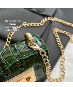 Close-up of dark green croc-effect bag featuring gold chain and detachable metal hook