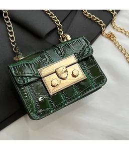 Close-up of deep green crocodile texture leather mini bag with gold chain and clasp