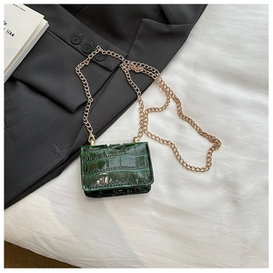 Detail of vintage dark green mini flap bag with glossy crocodile texture and gold chain
