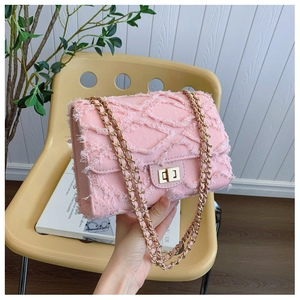 Detailed close-up of pink quilted denim handbag with frayed edges and gold chain strap