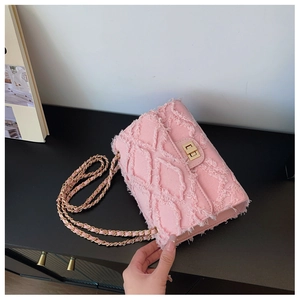 Close-up of pink denim crossbody bag with distressed quilted pattern and gold chain