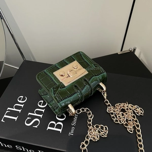 Detail of dark green crocodile texture mini bag with gold chain and metal clasp lock