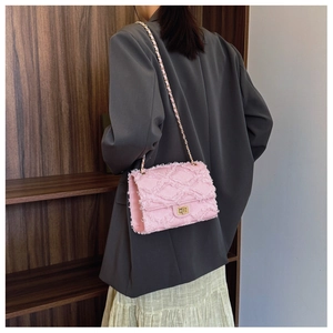 Pink denim crossbody bag with quilted fringe texture and golden chain on model's side