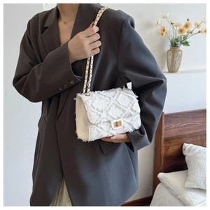 Detail of white tweed quilted crossbody bag with gold turn-lock and chain strap