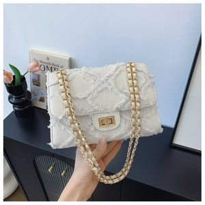 Detail shot of white quilted flap bag with frayed fringe edges and gold chain strap