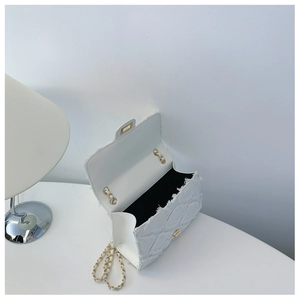 Detail of white quilted tweed bag with gold chain strap, twist lock and fringe edges