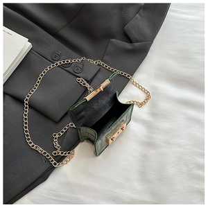 Detail view of mini green crocodile-pattern leather bag with golden chain and clasp