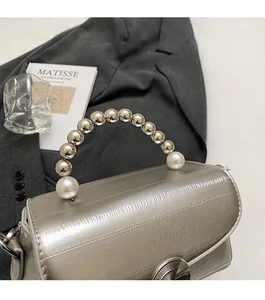 Detail of silver crossbody bag featuring a unique pearl and metal bead handle design