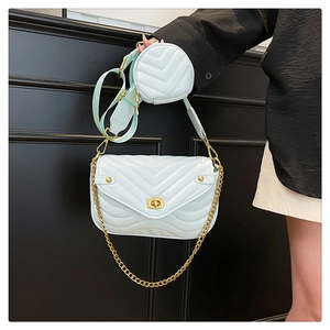 Detail of mint green quilted crossbody bag with gold chain and round coin purse attachment