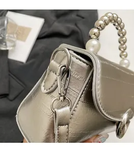 Detail of silver metallic leather handbag with V-quilting and pearl beaded handle