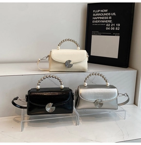 Three mini flap bags in off-white, black, and silver with beaded pearl top handles