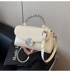 Detail of cream croc-effect mini bag featuring a stylish silver bead and pearl handle