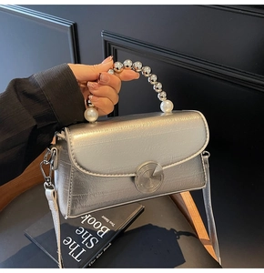 Detail of silver metallic handbag with pearl bead handle and circular metal buckle