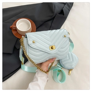 Detail of light blue V-quilted bag with gold clasp and wide green fabric strap