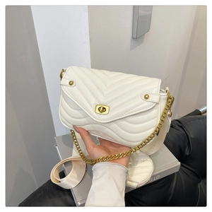 Close-up of quilted handbag texture with golden metal twist-lock and wide strap