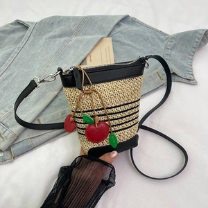 Contrast straw bucket bag with red cherry charm and adjustable black shoulder strap