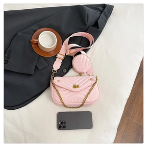 Pink quilted crossbody bag detail with wide shoulder strap and round coin purse accessory