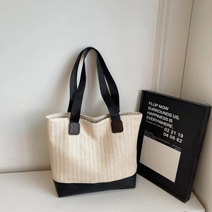 Minimalist straw woven tote bag with contrast black handles and base for summer