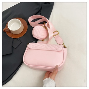 Detailed close-up of pink quilted crossbody bag with small round coin pouch and wide strap