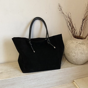 Minimalist black matte tote bag with drawstring detail on a stone surface