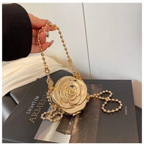 Détail d'un sac de soirée rose en acrylique doré avec pétales 3D et bandoulière en chaîne