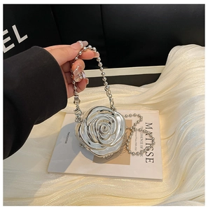 Vue détaillée du sac rose métallique argenté avec bandoulière à perles sur tissu satiné