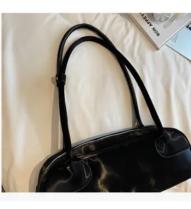 Detail of glossy black patent leather tote bag with slender straps and zipper closure