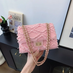 Pink frayed denim crossbody bag with gold chain strap and quilted fabric texture