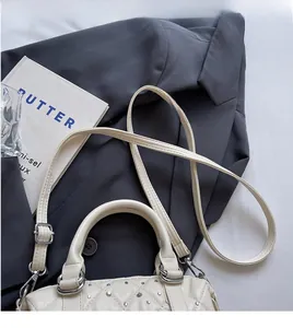 Detail of cream quilted Boston bag with silver studs and long adjustable shoulder strap