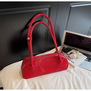 Detailed macro view of long cylindrical red hobo bag with sleek finish and metal snaps