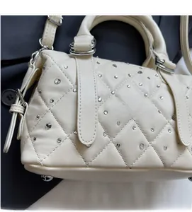 Detail of cream quilted Boston bag featuring sparkly rhinestones and silver ring handles