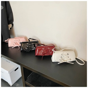 Row of patent leather shoulder bags in pink, black, red, and white on a wooden shelf