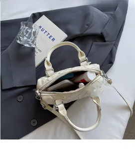 Interior view of off-white quilted handbag showing space for phone and makeup items
