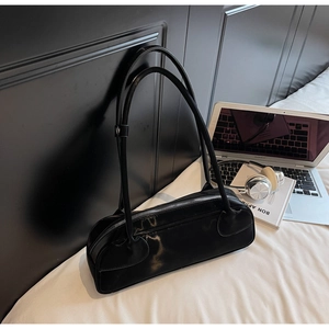 Minimalist black leather underarm bag with silver zipper in a modern lifestyle setting