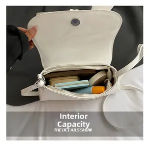 Internal capacity of white glossy shoulder bag showing makeup storage and magnetic closure