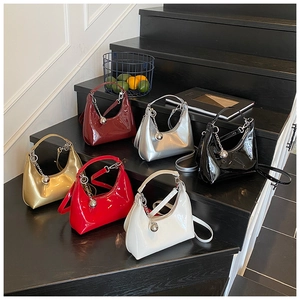 Détail de six sacs hobo en cuir verni brillant de différentes couleurs sur des marches en bois