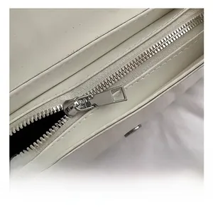 Close-up of premium silver metal zipper and rectangular puller on white leather bag