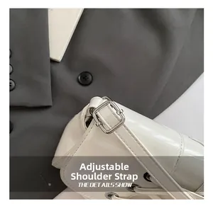 Detailed close-up of white glossy leather shoulder bag featuring an adjustable metal strap buckle