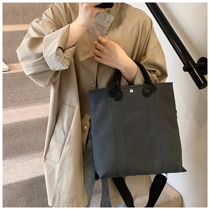 Detail of dark grey canvas tote bag with contrast black handles and adjustable shoulder strap