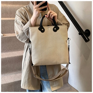 Detailed view of canvas tote bag with black leather handles and reinforced stitching