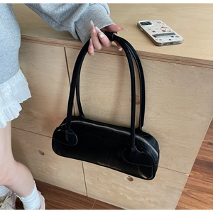 Detail of a minimalist black faux leather underarm bag with silver zipper and slim straps